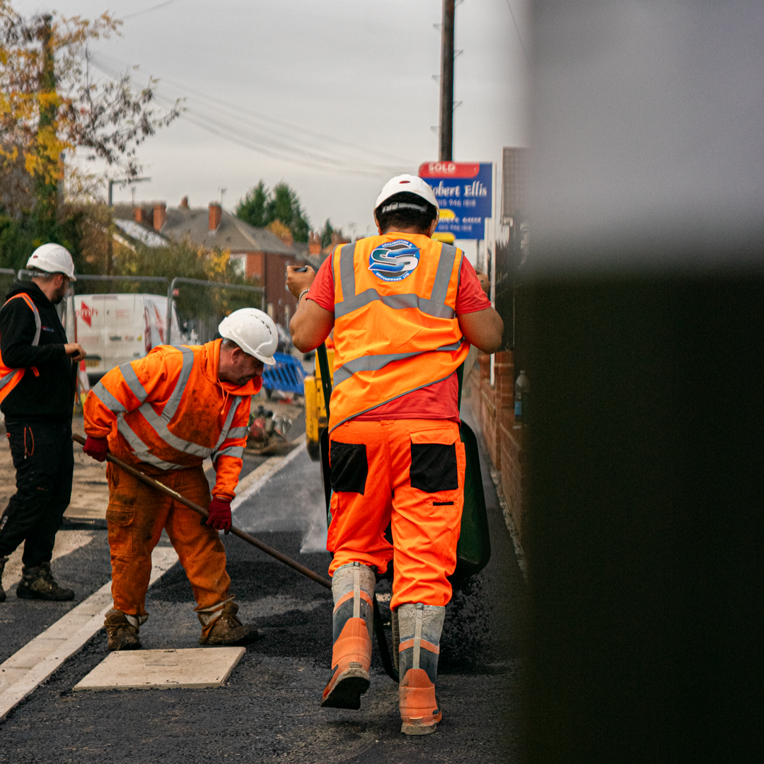 SS Construction operatives raking and laying tarmac on a residential road resurfacing job