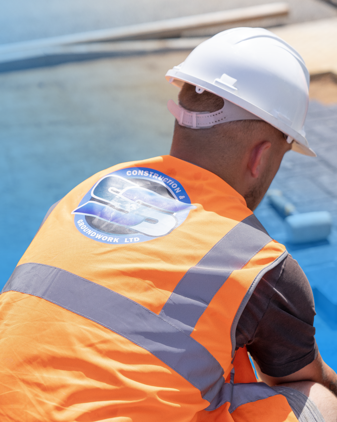 Close-up of an SS Construction team member wearing branded high-visibility clothing on a commercial site