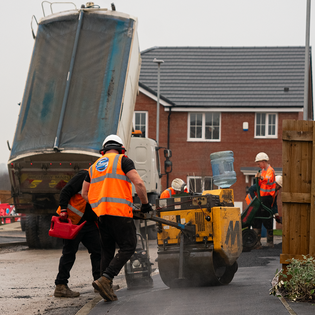 SS Construction team compacting a new tarmac driveway with a roller while a tipper truck unloads material